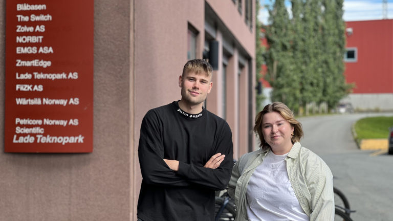 Mann og dame som smiler for kontorbygg i Trondheim