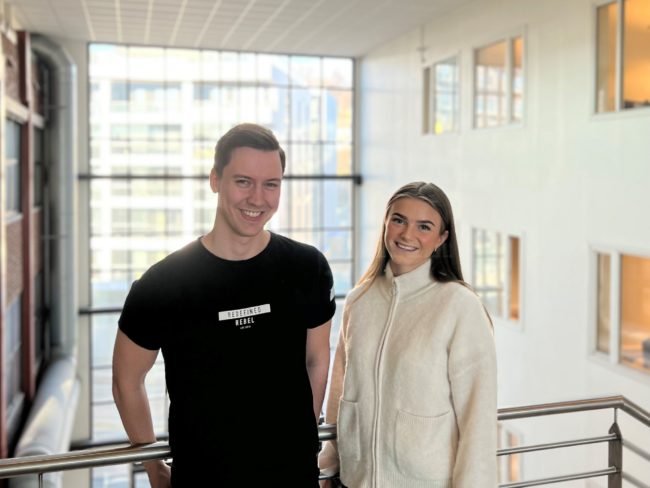 Mann og dame som smiler i kontorlokaler.