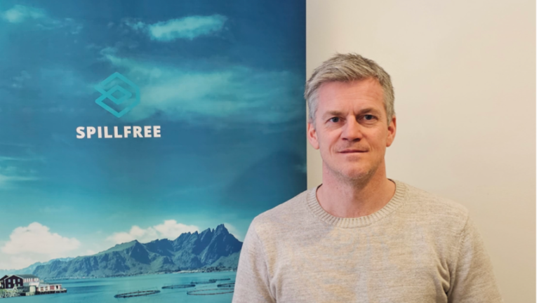 Mann som smiler foran en reklamebanner. Foto