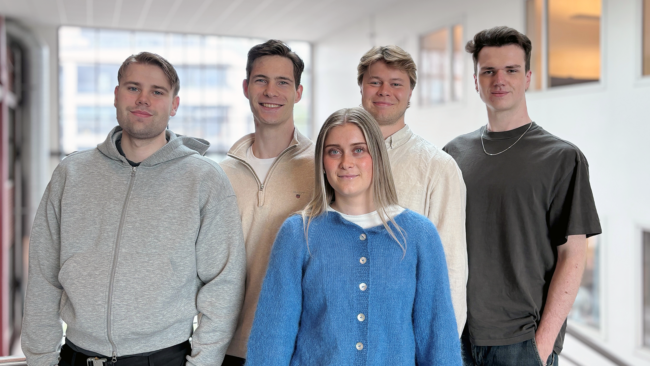 Gruppe med fem personer. Fire menn bak og ei dame foran.