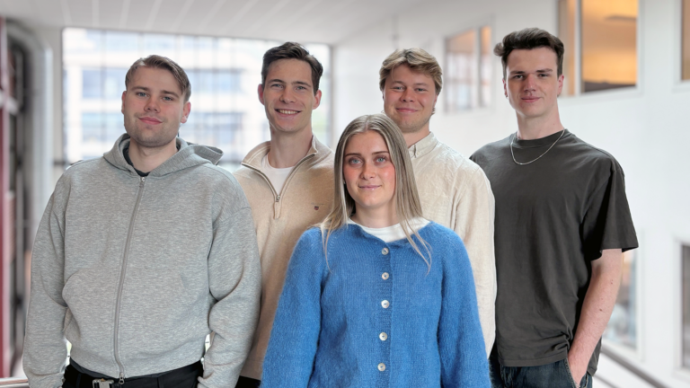 Gruppe med fem personer. Fire menn bak og ei dame foran.